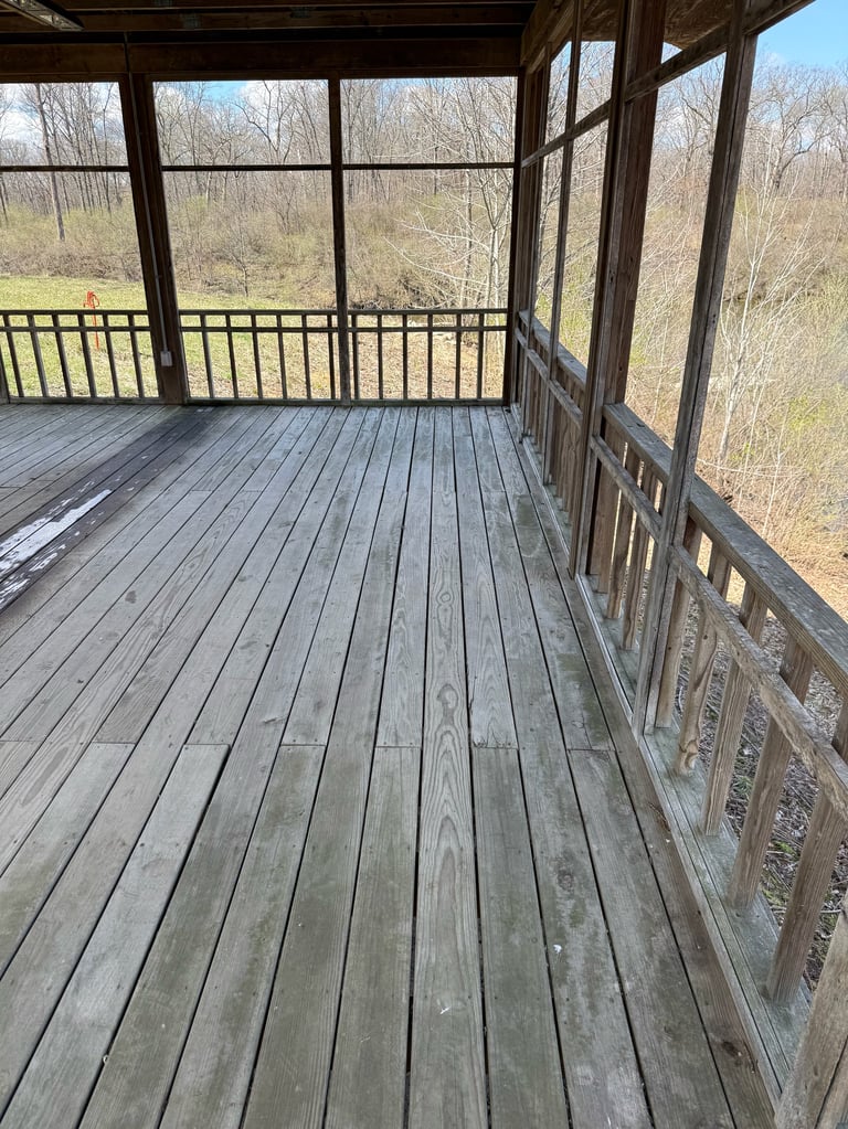 Empty screened porch with wooden deck overlooking bare trees and nature landscape