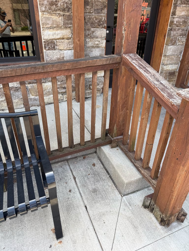 Traditional wooden entry gate with railings and concrete threshold leading to stone building