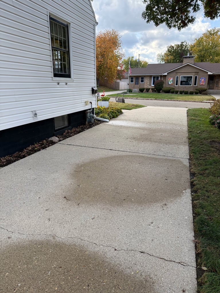 White trailer home with concrete driveway leading to a single-story brick house in a residential neighborhood