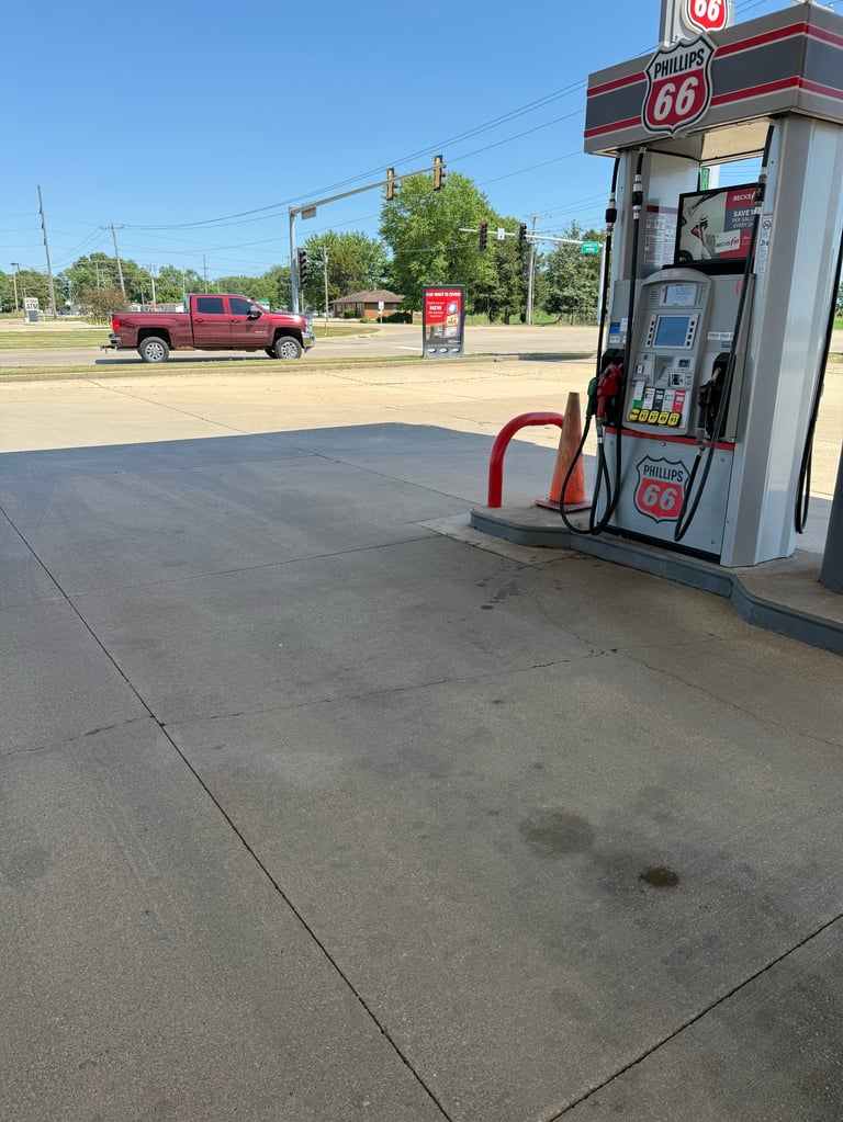 Vintage Phillips 66 gas pump at an empty rural filling station with a red truck and clear blue sky