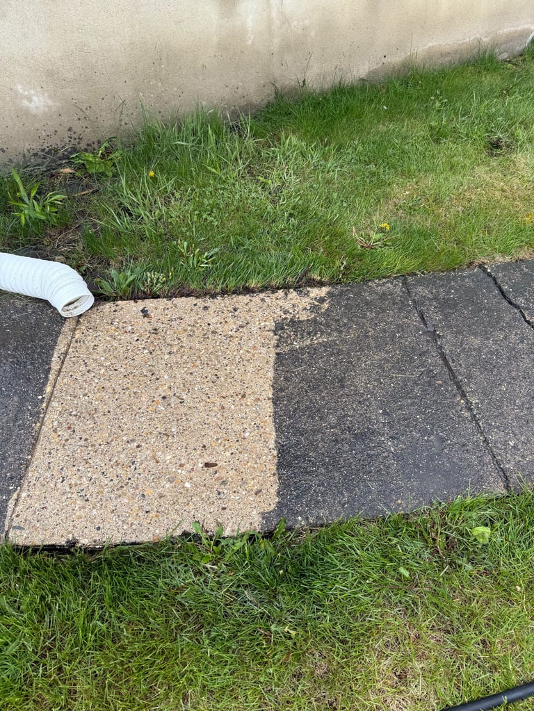 Two asphalt shingles placed on grass next to a concrete surface for roofing comparison